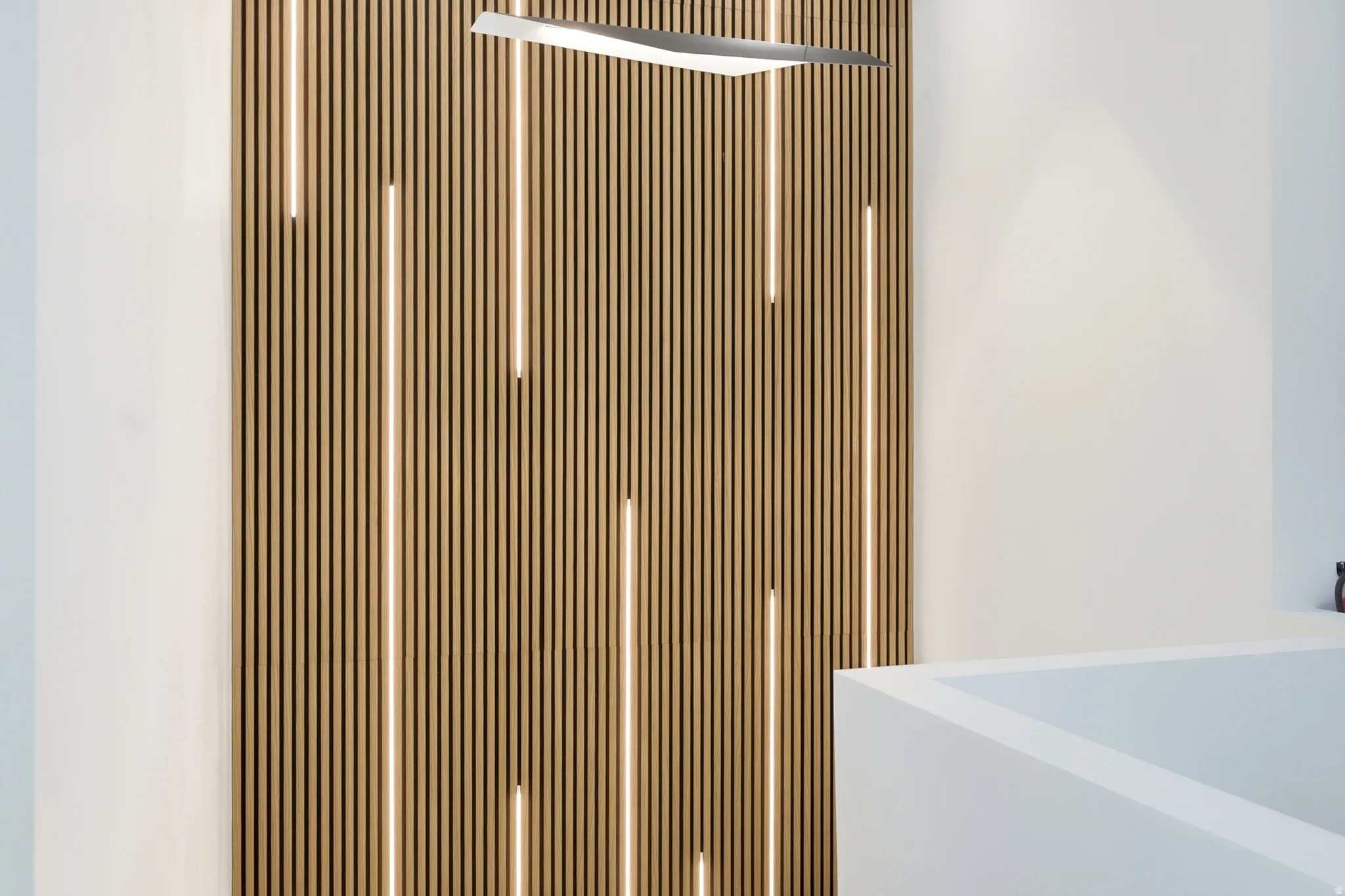 Wood-finish slat wall with integrated linear lighting and a modern linear light fixture
