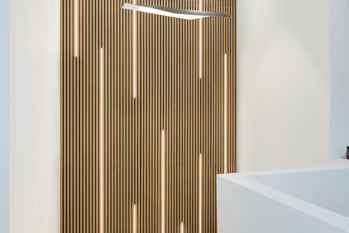 Wood-finish slat wall with integrated linear lighting and a modern linear light fixture