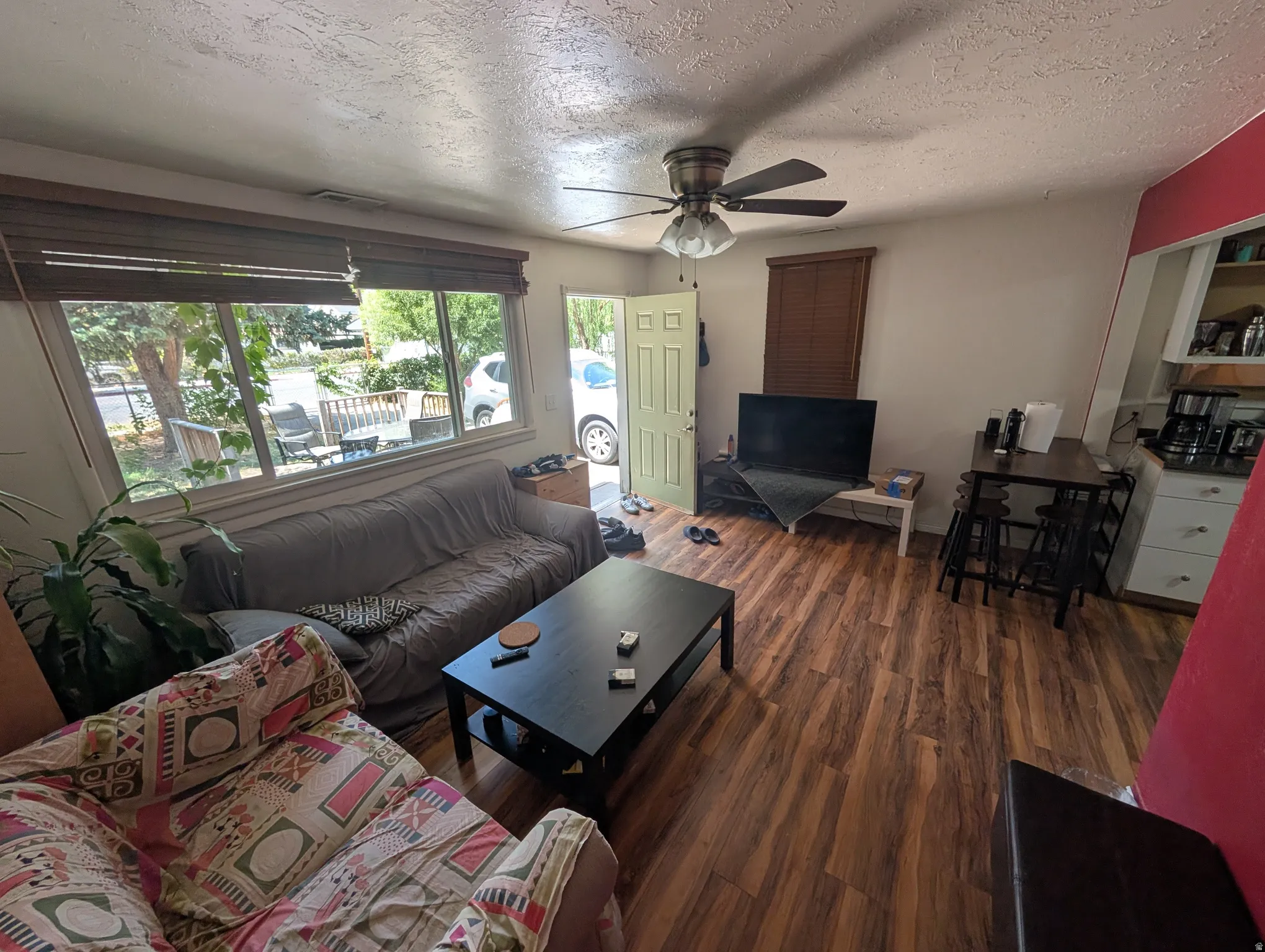 Living area featuring wood-finish flooring, a multi-pane window, and a ceiling fan with integrated lighting