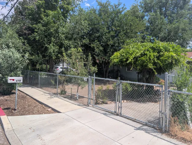 Chain link fence with double gate entry, sidewalk, and mail post
