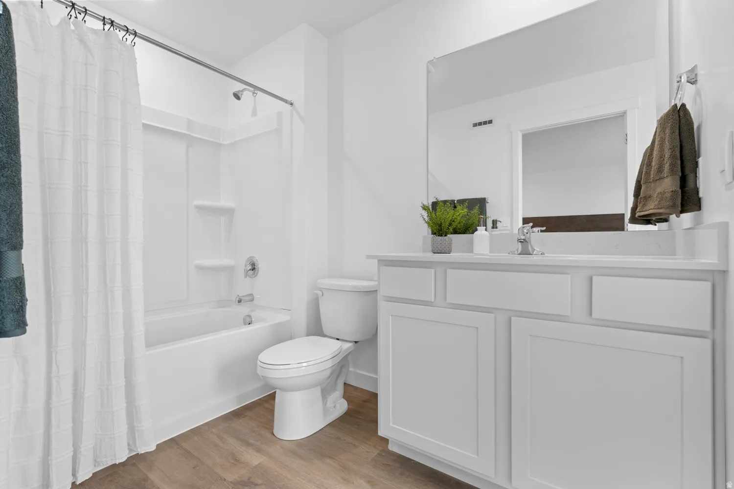 Bathroom featuring a white vanity with shaker-style cabinetry, a built-in sink, and a large mirror