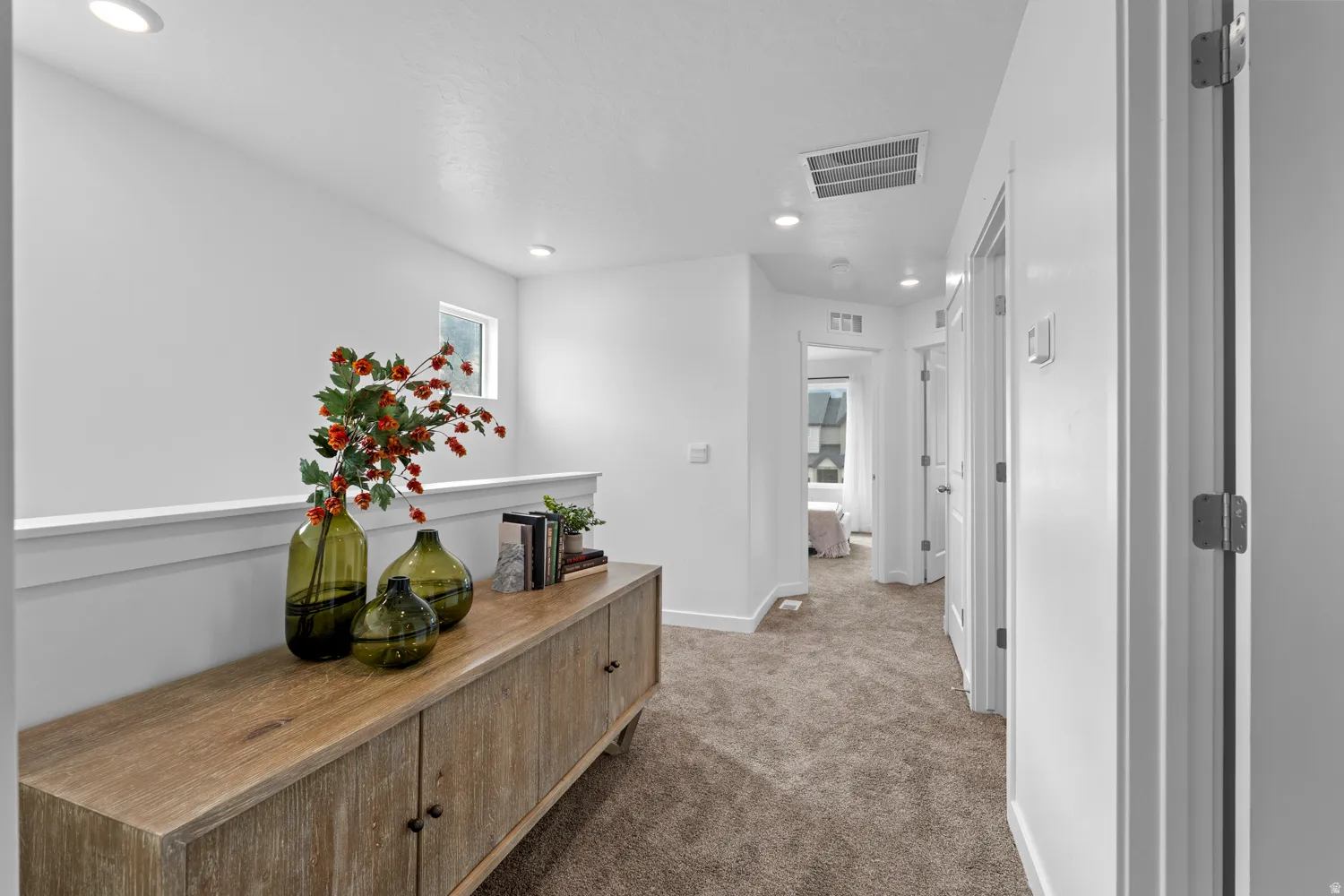 Bright hallway featuring neutral carpet flooring and white walls