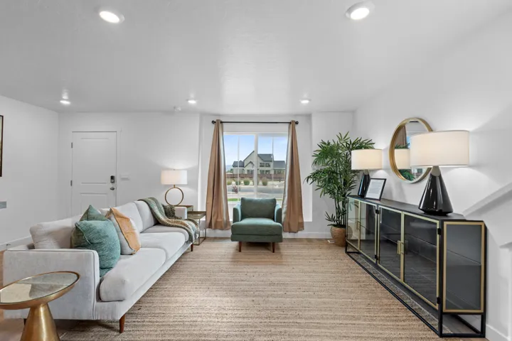 Bright living area featuring recessed lighting, a large window with neutral drapery, and a textured area rug