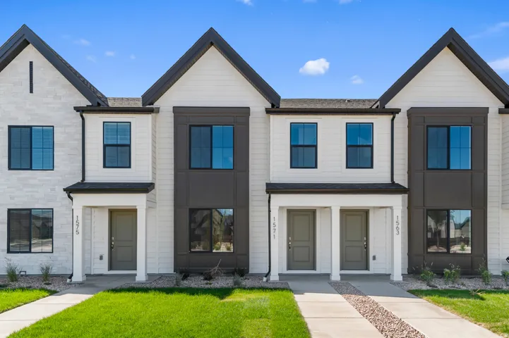 Contemporary townhome exterior featuring clean architectural lines, contrasting white siding with dark gray accents, and prominent black-framed windows
