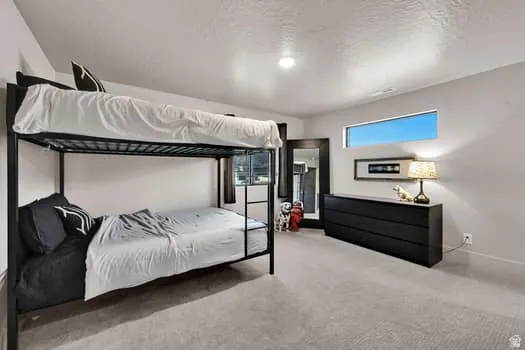 Carpeted room featuring a metal bunk bed, a long horizontal window, and a built-in wall niche