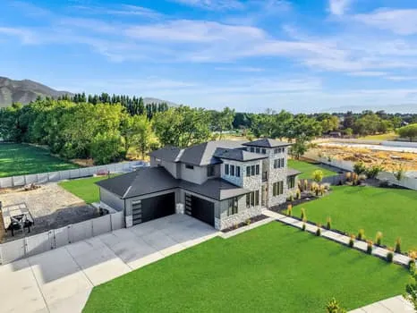 Contemporary multi-story residence featuring a stone and stucco exterior, a multi-car garage with modern doors, and a concrete driveway