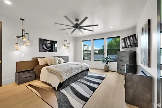 Spacious room featuring light wood-finish flooring, multiple windows with dark framing, and a ceiling fan