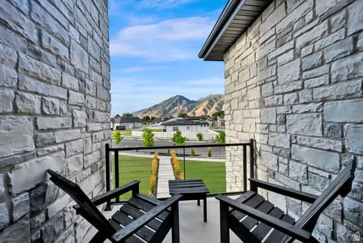 Private balcony with stone veneer walls, cable railing, and mountain scenery