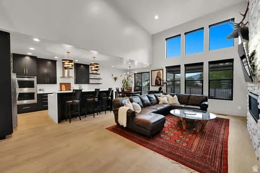 Expansive open-concept living area featuring high vaulted ceilings, large windows, and light wood-finish flooring