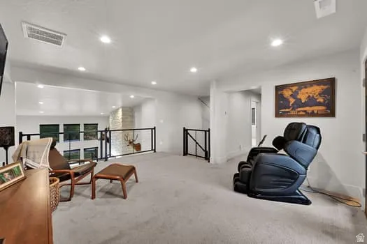 Spacious loft area featuring light gray carpeting, recessed lighting, and a contemporary black metal railing overlooking the lower level