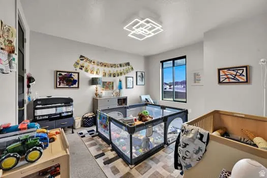Spacious room featuring light gray walls, a contemporary geometric ceiling light fixture, and a large window with black framing