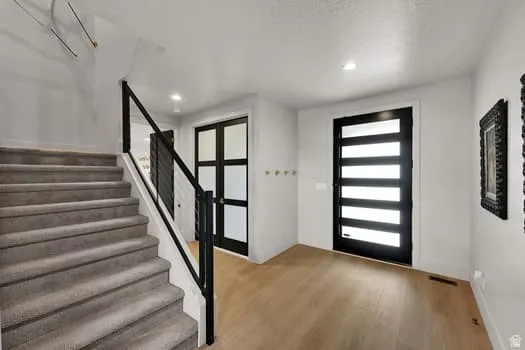 Entryway featuring a modern black front door with horizontal lites, light wood-finish flooring, and recessed lighting