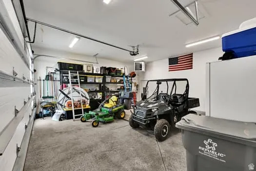 Spacious garage featuring a concrete floor, overhead lighting, and white walls