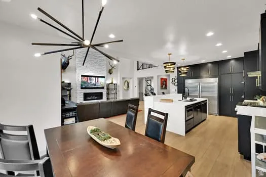 Open-concept living area featuring a spacious kitchen with dark cabinetry and stainless steel appliances, a large center island with white countertop, and wood-finish flooring