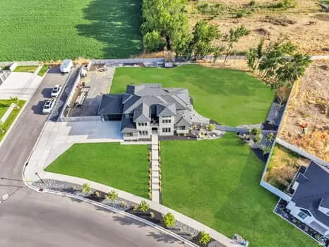 Spacious property featuring a large residence, expansive green lawn areas, and a paved driveway