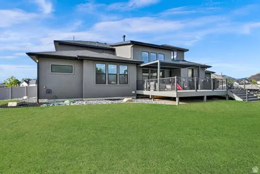 Modern stucco exterior featuring a multi-level deck with metal railings and an integrated patio cover