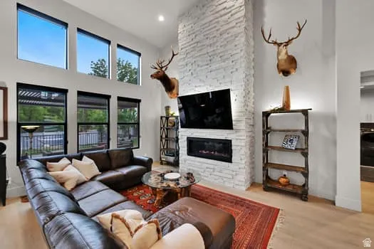 Living area with a floor-to-ceiling stacked stone fireplace, integrated linear electric fireplace, and high ceilings