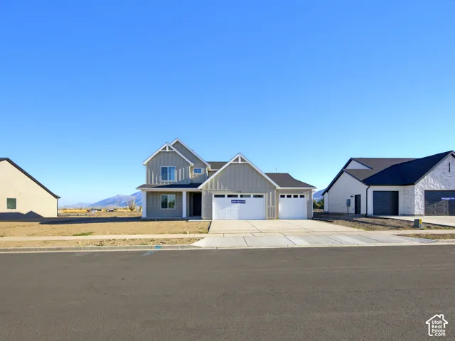 Two-story exterior featuring vertical board-and-batten siding, a gabled roofline, a three-car garage, and a concrete driveway