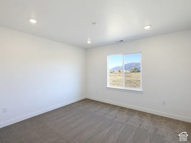 Interior space featuring neutral wall tones, carpeted flooring, recessed lighting, and a window framing mountain scenery