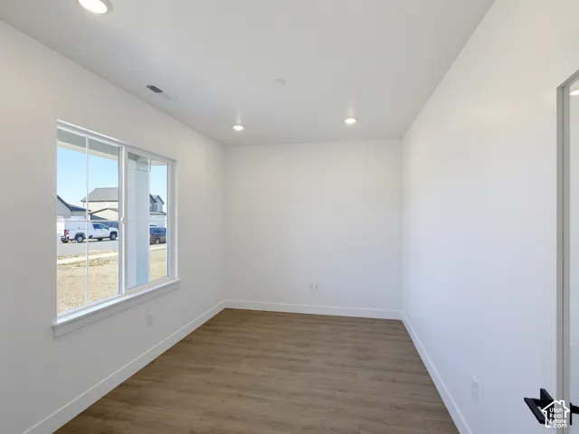 Room interior featuring neutral walls, wood-finish flooring, recessed lighting, and a large sliding window with grid detailing