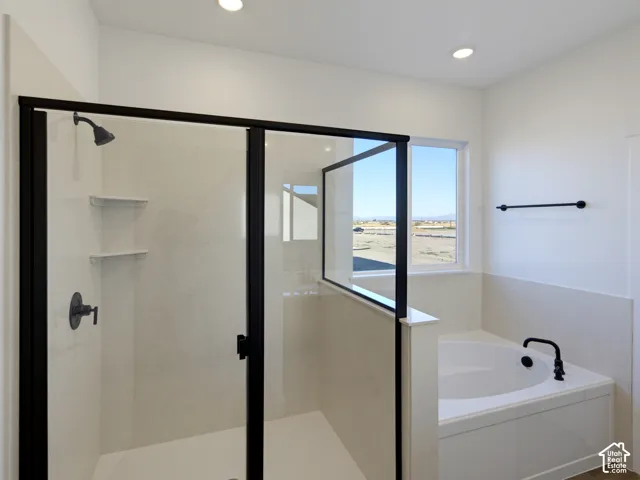 Walk-in shower with a black metal frame, integrated stone-finish surround, and built-in shelving, paired with a deep soaking tub featuring black hardware, recessed lighting, and a neutral tile surround