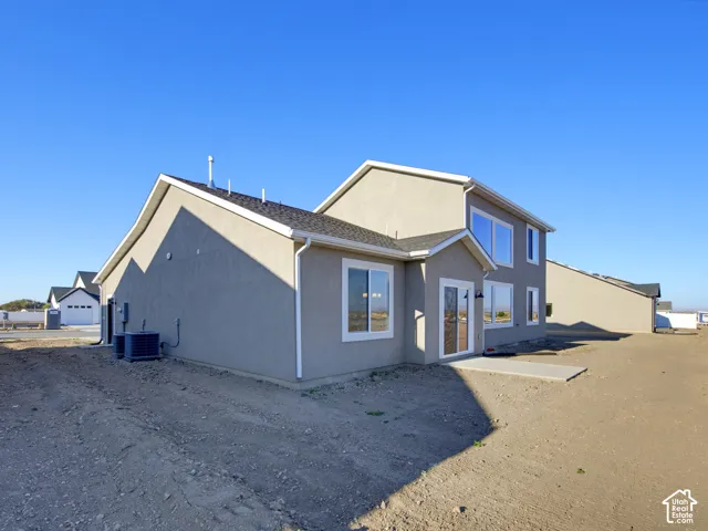 Two-story exterior featuring stucco siding, a multi-gabled roofline, sliding glass doors, and a concrete rear patio