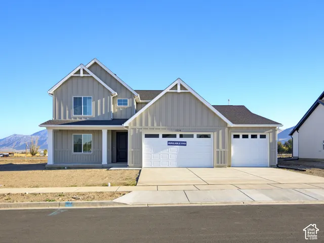 Two-story exterior featuring vertical siding, a covered front entry with columns, a three-car garage, and mountain scenery