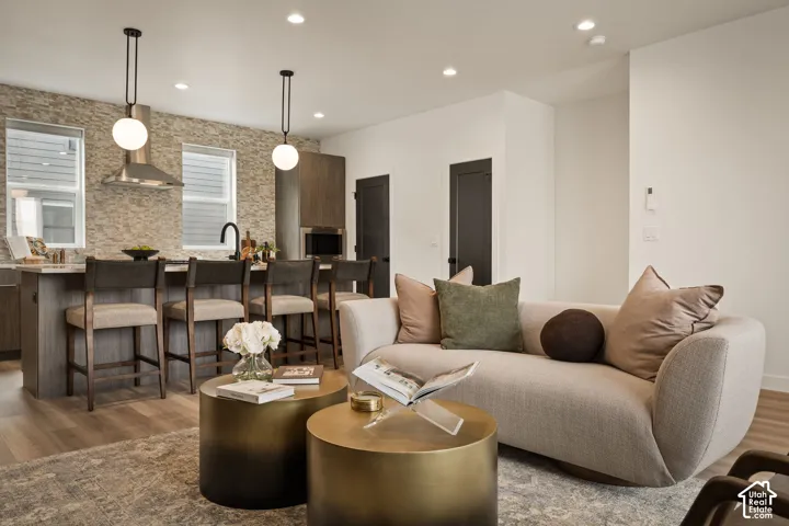 Kitchen featuring a stacked stone backsplash, wood-finish cabinetry, built-in stainless steel appliances, pendant globe lighting, and recessed ceiling lights