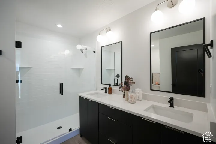 Double vanity featuring matte black hardware, quartz countertops, rectangular undermount sinks, and two framed mirrors with integrated lighting