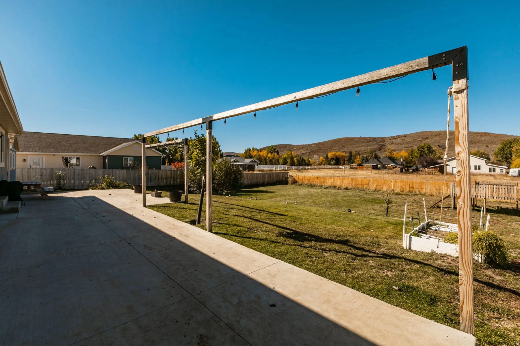 Expansive concrete patio with a wooden pergola frame