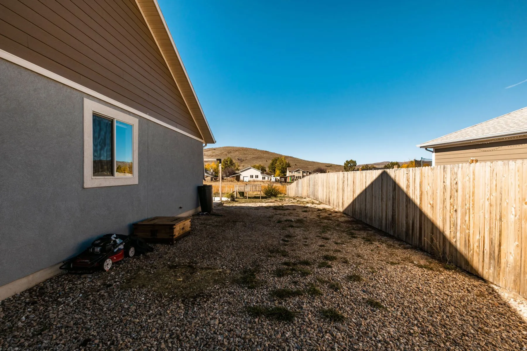 Exterior property area featuring a light gray stucco finish, horizontal brown siding, and a white window trim