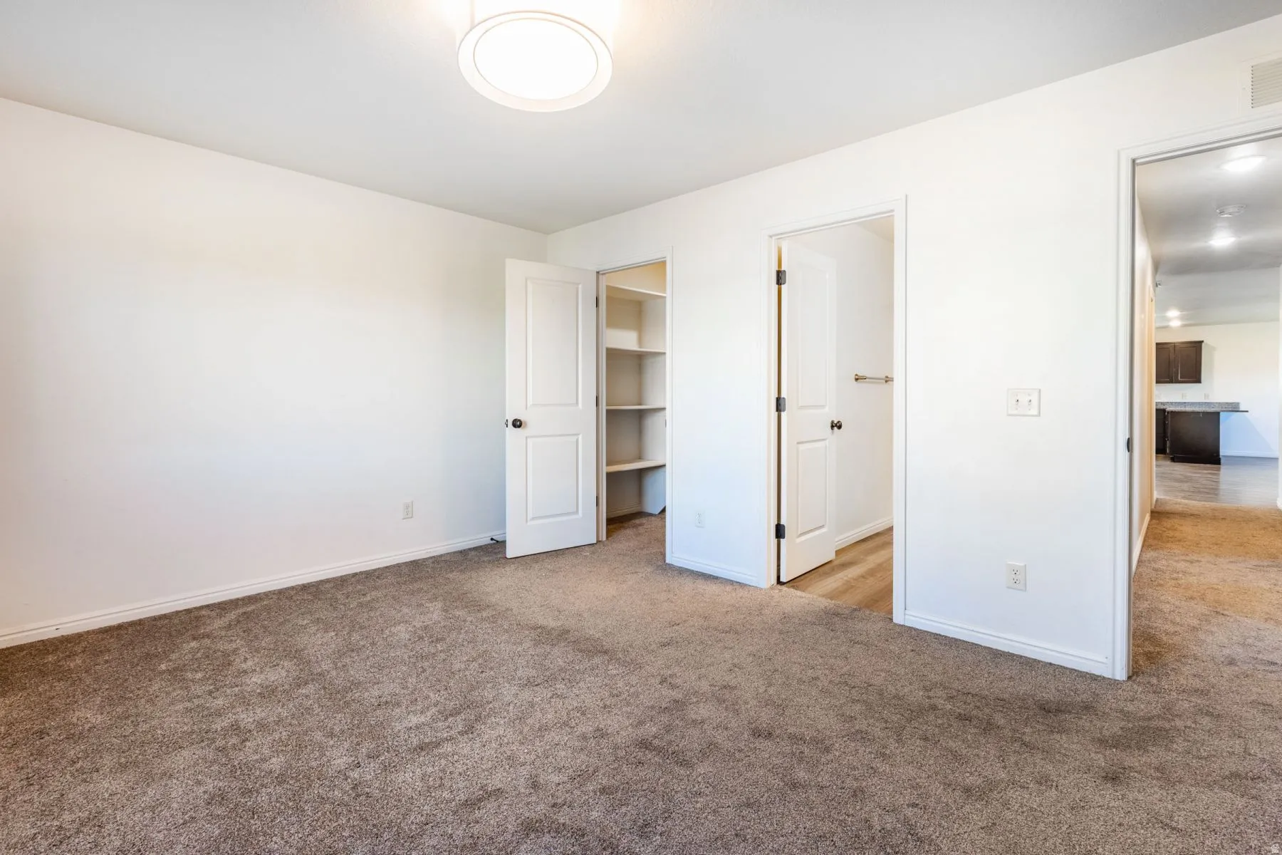 Carpeted room featuring a ceiling-mounted light fixture and white baseboards