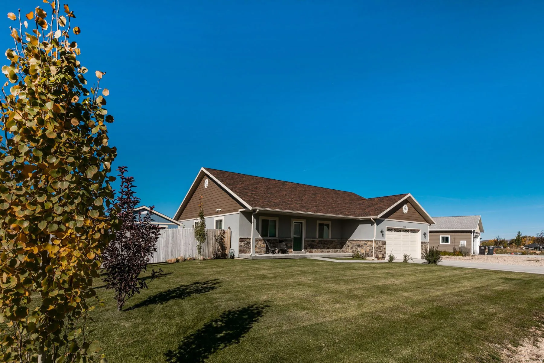 Exterior featuring a light grey siding, brown shingle roof, and a stone facade accent
