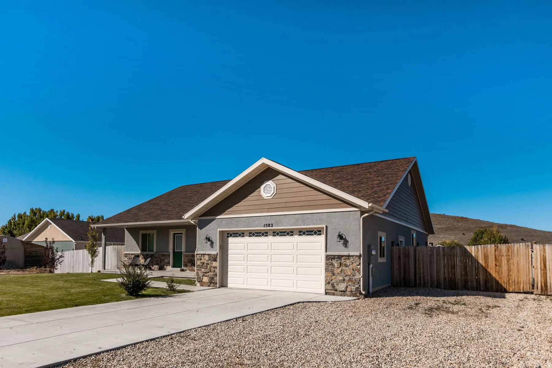 Ranch-style exterior featuring a attached two-car garage, stone and stucco facade, and a paved driveway
