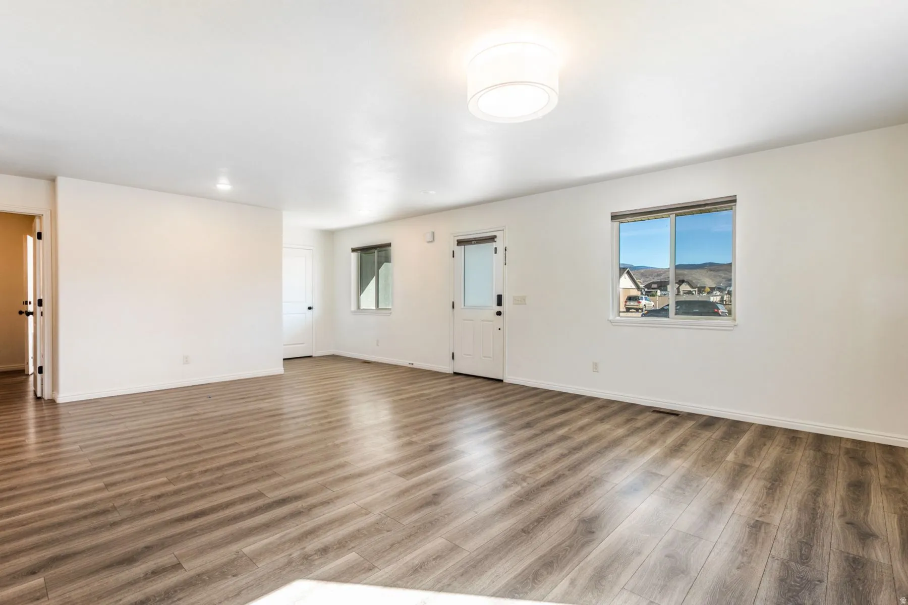 Spacious interior featuring wood-finish flooring, white walls, and a recessed ceiling light