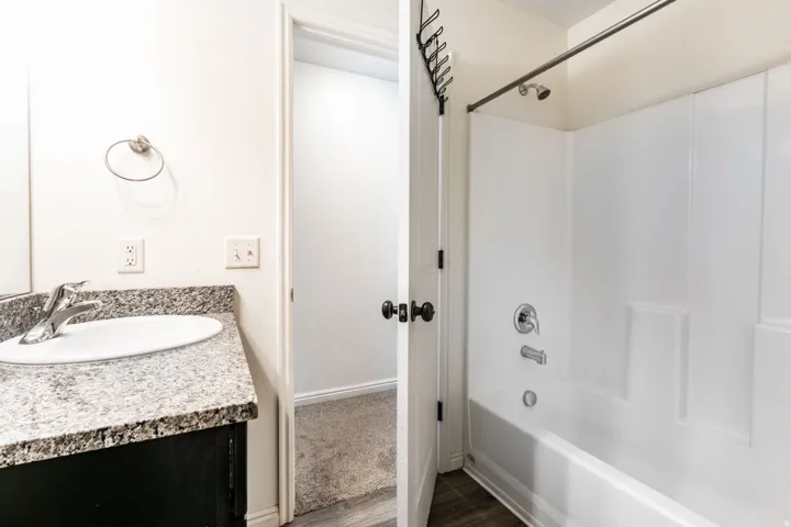 Bathroom featuring a white integrated sink, stone-finish countertop, and dark wood-finish vanity