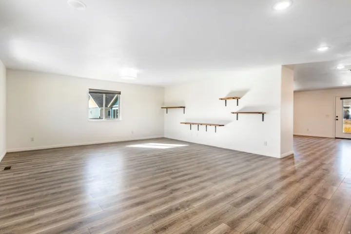 Spacious room featuring wood-finish flooring, white walls, recessed ceiling lighting, and a large window