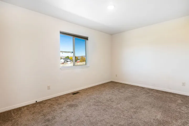 Carpeted room featuring a single window with a window treatment, light-toned walls, white baseboards, and an overhead light fixture