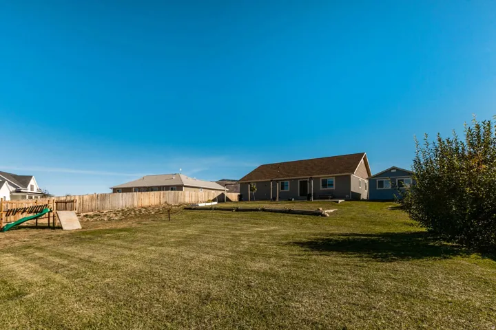 Expansive backyard with a manicured lawn, established privacy fencing, and mature shrubbery