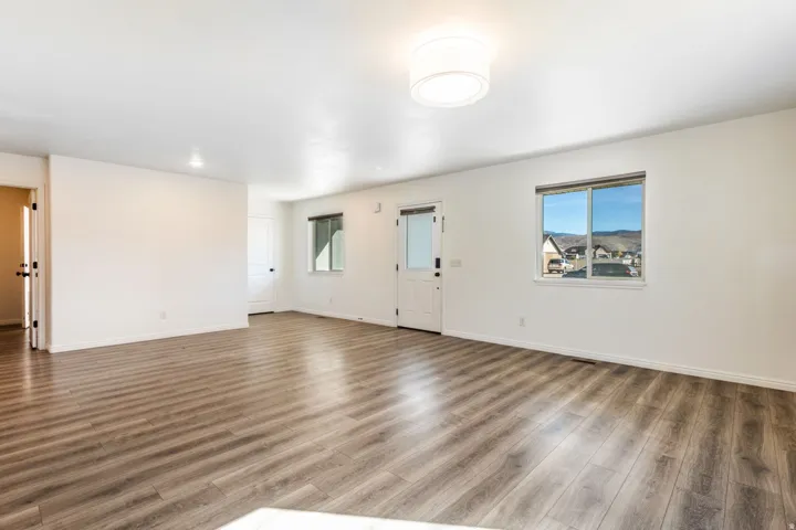 Spacious interior featuring wood-finish flooring, white walls, and a recessed ceiling light
