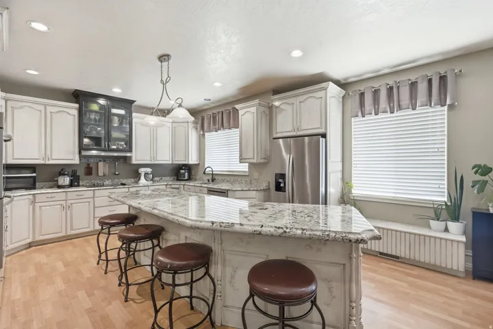 Kitchen featuring a large island with a stone countertop, light wood-finish flooring, recessed lighting, white cabinetry, and stainless steel appliances