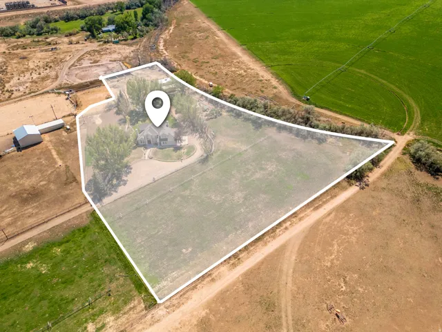 Expansive property featuring a central residence, outbuilding, and varied terrain including cultivated fields