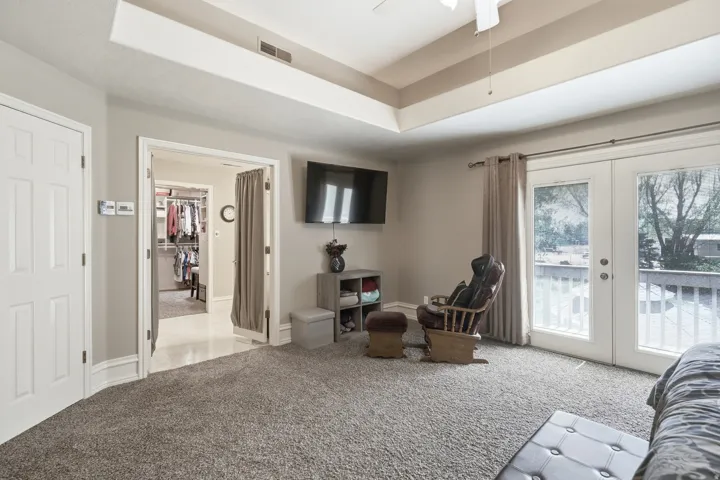Tray ceiling, French doors, private balcony, walk-in closet with built-in shelving, and neutral carpeting