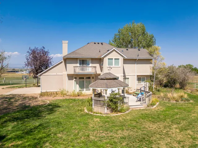 Rear exterior with a second-story balcony, a detached gazebo with a built-in deck, and a stucco finish