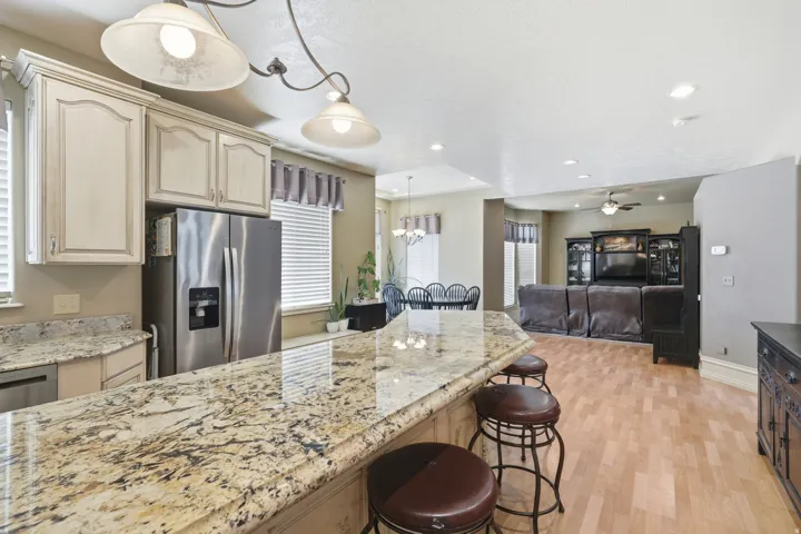 Kitchen featuring a multi-toned stone countertop, stainless steel refrigerator, and pendant lighting