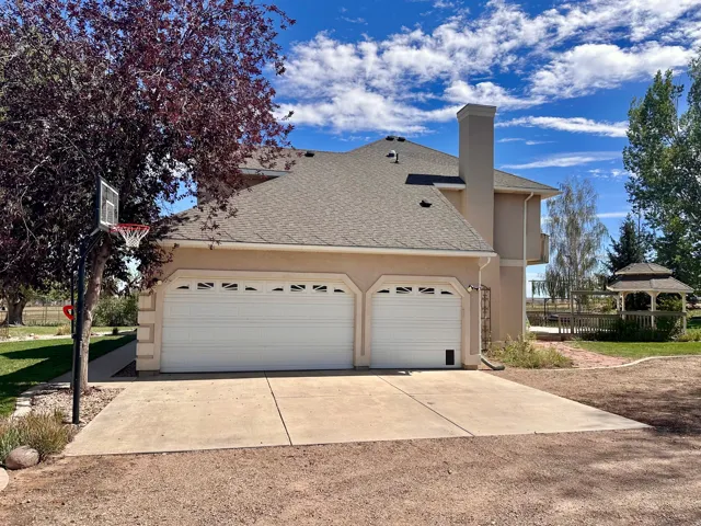 Stucco exterior with a two-car garage, concrete driveway, and covered gazebo