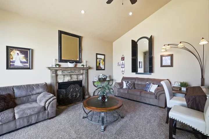 Living area featuring a fireplace with an ornate mantel, a vaulted ceiling, recessed lighting, and a ceiling fan