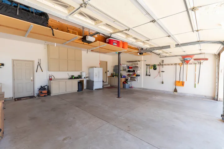 Spacious garage with concrete flooring, overhead storage shelving, built-in cabinetry, and wall-mounted shelving