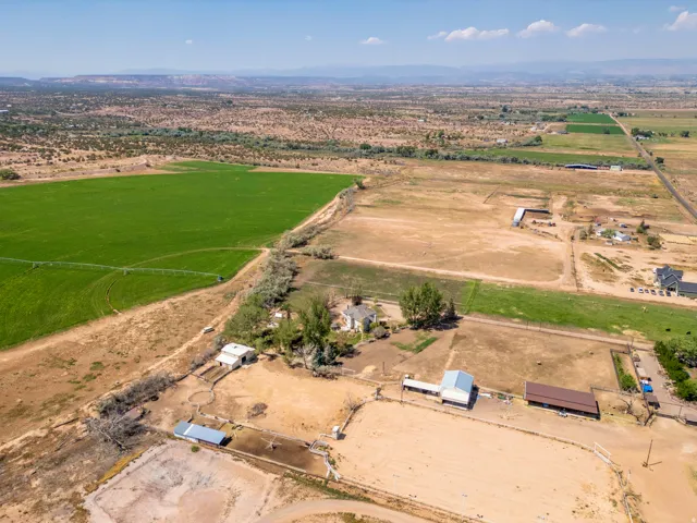 Expansive property with multiple outbuildings, fenced areas, and a large agricultural field
