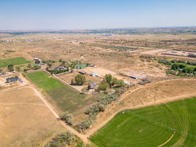 Expansive acreage featuring multiple structures, a pond, and cultivated fields